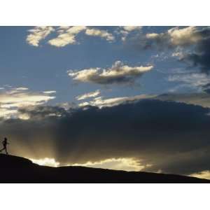  Silhouetted Figure Trail Running under a Cloud Filled Sky 