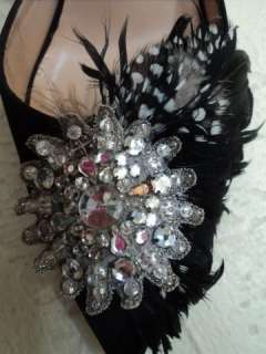 Black satin pump with feather and with a rhinestone detail .